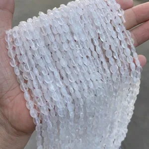 Macro detail of faceted natural white quartz beads in oval shape for DIY jewelry designs.