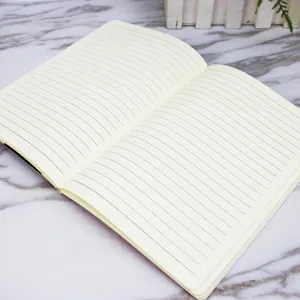 Detailed close-up of an open lined notebook on a marble table surface for writing notes.