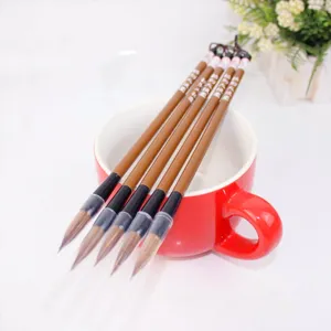Detailed shot of Chinese calligraphy brushes with transparent tip covers in a red mug.