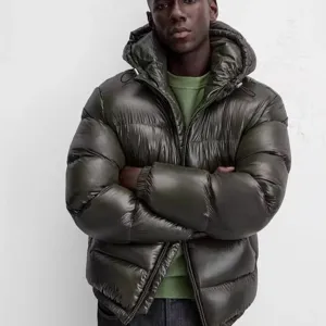 Men's glossy olive green puffer jacket detail, hooded winter outerwear close up display.