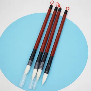 Set of 4 Chinese calligraphy brushes with protective caps and red hanging cords for writing.