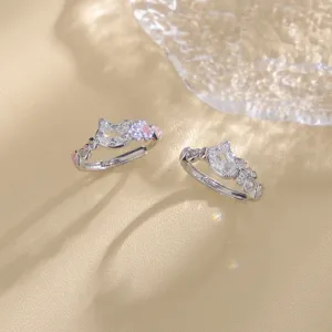 Close-up of cat-shaped silver rings with pink zircon paws and clear crystal centers.