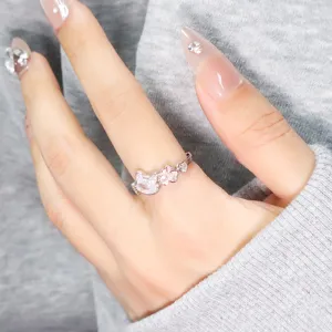 Macro detail of a silver cat-themed ring featuring pink zircon and heart motifs.