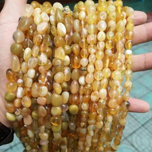 Primer plano de cuentas de ámbar natural irregulares para joyería DIY en la mano.