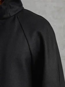 Gros plan detail du tissu d epaule de manteau en laine noire homme et design de manche raglan.