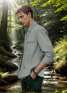Männliches Model trägt eine hellgraue, minimalistische dünne Hemdjacke im Wald am Bach