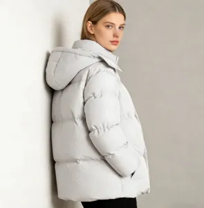 Détails rapprochés de la veste d'hiver matelassée unie et ample à capuche gris clair.