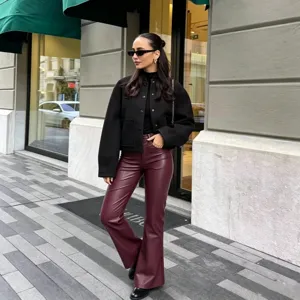Women's autumn fashion black stand collar jacket with stylish burgundy leather pants.