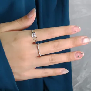 Detailed shot of a moonstone little devil open ring and a thin sparkling band on a finger.