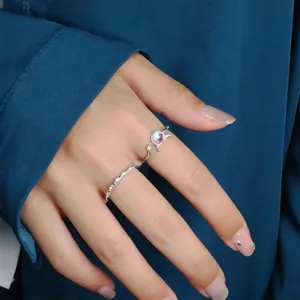 Detailed view of a cute silver open ring with moonstone and a sparkling band on a hand.