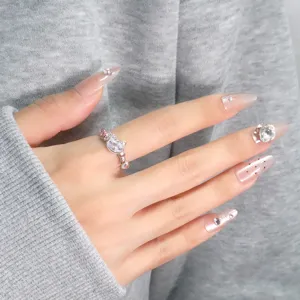Detailed view of a cute pink zircon cat ring featuring heart and paw motifs on a hand.
