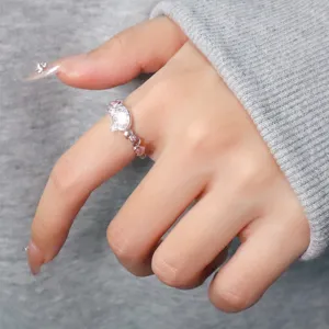 Detailed close-up of a silver cat ring featuring pink zircon heart details on a finger