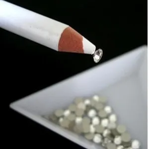 Macro view of a professional white picker pencil tool picking up a crystal rhinestone