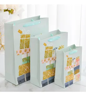 Three sizes of light green paper gift bags with gold foil patterns and silk handles.