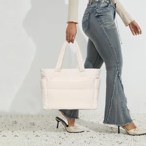 Model carrying a lightweight off-white quilted puffer tote bag for travel and fitness