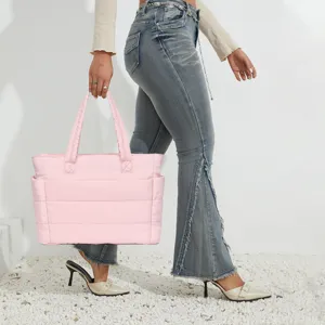 Side view of a pink lightweight quilted travel tote bag being carried by a walking model