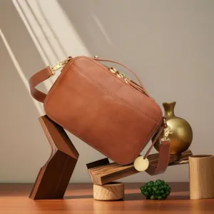 Detailed view of a vintage brown leather camera bag with elegant gold hardware