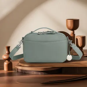 Detailed macro view of a vintage sage green leather camera bag on a wooden display stand