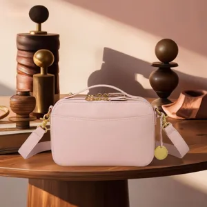 Detailed view of a vintage pink pebbled leather crossbody camera bag with gold hardware