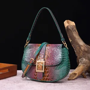 Detalle de piel con relieve de cocodrilo iridiscente verde y morado con hebilla dorada.