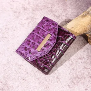 Primer plano de cartera vintage morada con estampado de cocodrilo y cierre dorado