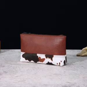 Detalle de bolso estilo western con cuero sintético marrón y estampado de vaca.
