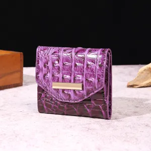Detalle de una cartera vintage morada con grabado de cocodrilo y diseño de tres pliegues para mujer