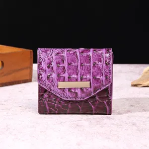 Vista de cerca de la cartera de cuero de cocodrilo púrpura para mujer con detalle metálico