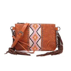 Detalle de un bolso bandolera boho de cuero repujado con flecos y tachuelas metálicas.