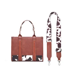Detalle de bolso retro de cuero sintético con estampado de vaca y correa ancha
