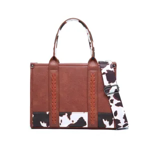 Detalle de este bolso tote vintage de cuero marrón con diseño de estampado vaca.