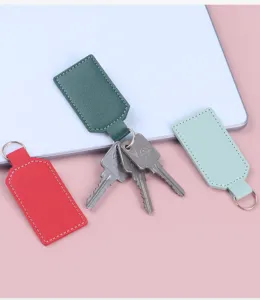 Nahaufnahme von PU-Leder-Schlüsselanhängern in Rot, Grün und Mint auf Pastellhintergrund.