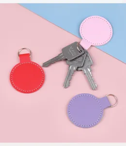 Gros plan de porte-clés ronds en cuir colorés avec surpiqûres fines et anneaux métal
