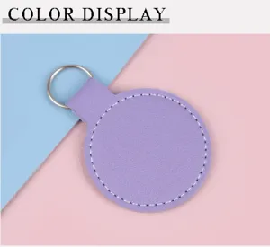 Détail d'un porte-clés rond en similicuir violet avec coutures blanches sur fond bicolore bleu rose