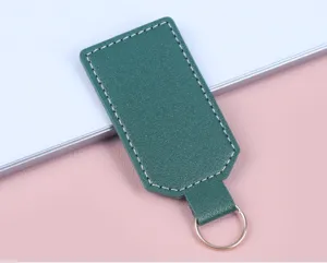 Detailansicht eines grünen PU-Leder-Schlüsselanhängers mit weißen Nähten und Metallring