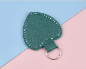 Makro-Detail eines grünen herzförmigen Leder-Schlüsselanhängers mit weißen Nähten
