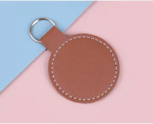 Gros plan d'un porte-clés circulaire en cuir marron avec surpiqûres blanches sur fond