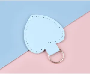 Detailaufnahme eines hellblauen Herz-Schlüsselanhängers aus Leder mit Ziernähten.