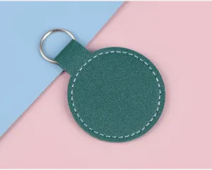 Vue détaillée d'un porte-clés rond en similicuir vert foncé avec couture blanche