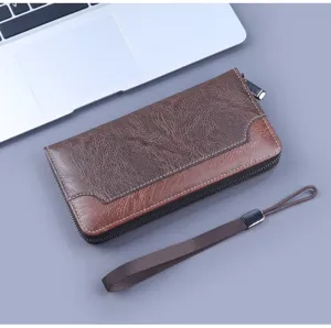 Detail view of a brown textured men's long wallet with a zipper and wrist strap.