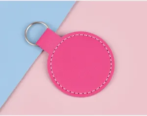 Vue détaillée d'un porte-clés circulaire en similicuir fuchsia avec surpiqûres blanches