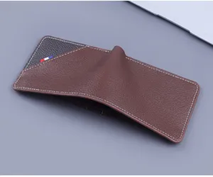 Detalle de una billetera de hombre en cuero granulado marrón con costuras blancas.