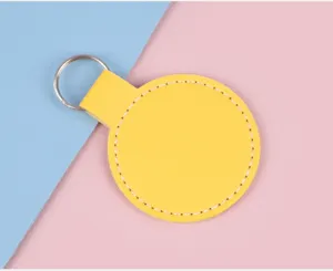 Gros plan d'un porte-clés circulaire en cuir jaune vif avec des coutures blanches fines.