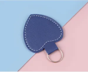 Nahaufnahme eines blauen Herz-Leder-Schlüsselanhängers mit Naht auf pastellfarbenem Grund