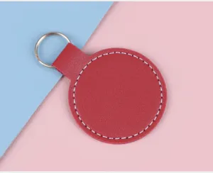 Gros plan d'un porte-clés circulaire en cuir rouge avec coutures blanches sur fond rose et bleu