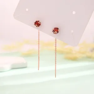Nahaufnahme von eleganten Roségold-Durchzieher-Ohrringen mit roten Zirkonia-Würfeln
