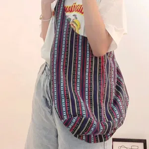 Primer plano de un bolso de hombro de lona a rayas aztecas vintage usado por una modelo