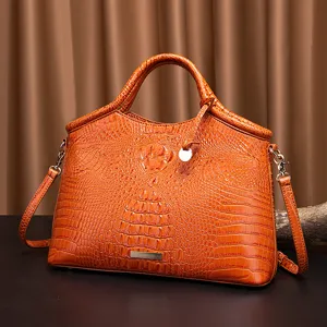 Vista detallada de un bolso vintage naranja con textura de cocodrilo en relieve