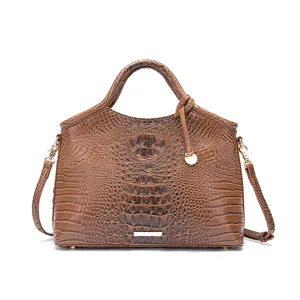 Detalle de un bolso vintage marrón con textura de cocodrilo y detalles dorados.