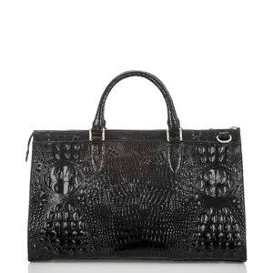 Primer plano de un bolso de mano de cuero negro con relieve de cocodrilo y herrajes dorados